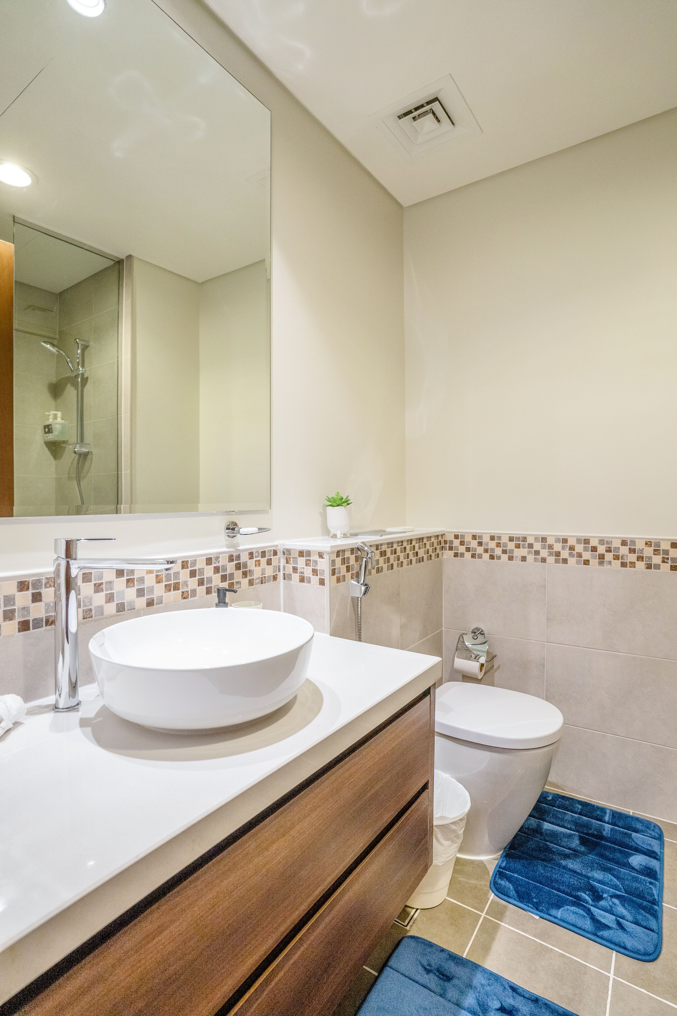 Une salle de bain moderne avec un lavabo rond, des toilettes, une douche et un miroir.