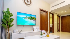 Ein modernes Wohnzimmer mit Flachbildfernseher, weißem Konsolentisch, Blumentopf und dekorativer Vase.