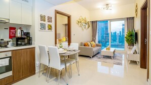 Eine moderne Wohnung mit Essbereich, Küche, Wohnzimmer und einem Balkon mit Blick auf die Stadt.