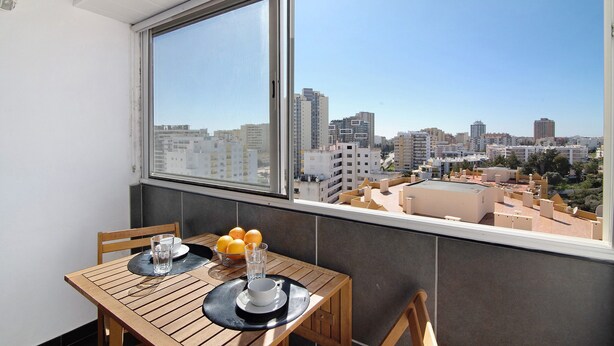 Un balcón con mesa, sillas y vistas a un paisaje urbano.
