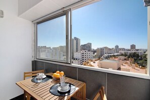 A balcony with a table, chairs, and a view of a cityscape.