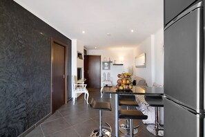 A modern kitchen with a central island, bar stools, and a refrigerator.