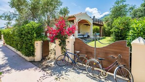 Une propriétéClose-up of a bicycle parked outside a gated property, with a covered patio area and lush greenery.
