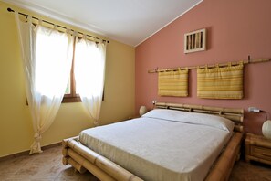 Ein Schlafzimmer mit Bett, Vorhängen, einem Nachttisch und einer Wandlampe.