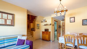 A living room with a sofa, dining table, chairs, a chandelier, and a staircase. - Apartment "Blanes" close to the Sea with Shared Pool (Blanes)