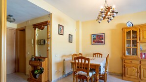 A dining area with a wooden table, chairs, a chandelier, a cabinet with glass doors, and a radiator. - Apartment "Blanes" close to the Sea with Shared Pool (Blanes)