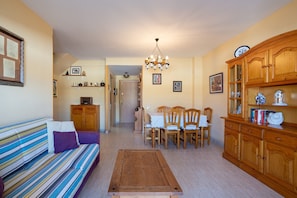 A living room with a sofa, dining table, chairs, wooden cabinet, and a chandelier. - Apartment "Blanes" close to the Sea with Shared Pool (Blanes)