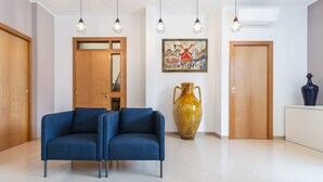 A modern room with two blue armchairs, a large vase, and a painting on the wall. - Alchemy Apartment (Conversano)