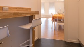 Una cocina moderna con encimera de madera, un taburete de bar blanco y un comedor con mesa y sillas.