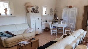 Un accogliente soggiorno con un divano, un baule di legno e una zona pranzo con tavolo e sedie.