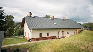 Une maison à deux étages, avec un toit en pente, une cheminée et un petit porche.