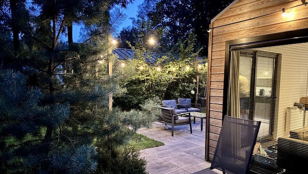 Un patio con terraza de madera, un conjunto de asientos y una pequeña mesa.