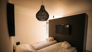 Una habitación de hotel con dos camas individuales, un televisor montado en la pared y una lámpara colgante.