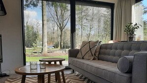 Una sala de estar moderna con un sofá gris, una mesa de centro redonda de madera y un tapete con estampado en zigzag.