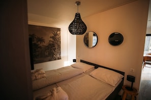 Ett sovrum med två sängar, en stor tavla, två speglar som hänger på väggen och en hängande lampa.