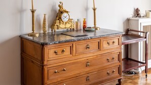 A wooden dresser with drawers, a marble top, and a brass clock.