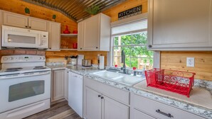 A kitchen with white cabinets, a stainless steel microwave, a stove, and a sink. - Kay's Cabin - Peaceful Acres (Rogersville)