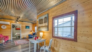 A cozy cabin interior with wooden walls, a dining area, a living room, and a large window. - Kay's Cabin - Peaceful Acres (Rogersville)
