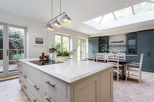 A modern kitchen with a large island, white cabinetry, and a skylight.