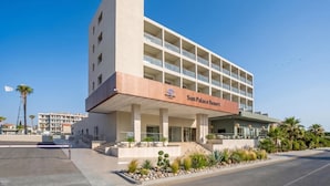 Um hotel com vários andares e um grande letreiro 'Sun Palace Resort', apresentando um design arquitetônico moderno com telhado plano e uma série de varandas.