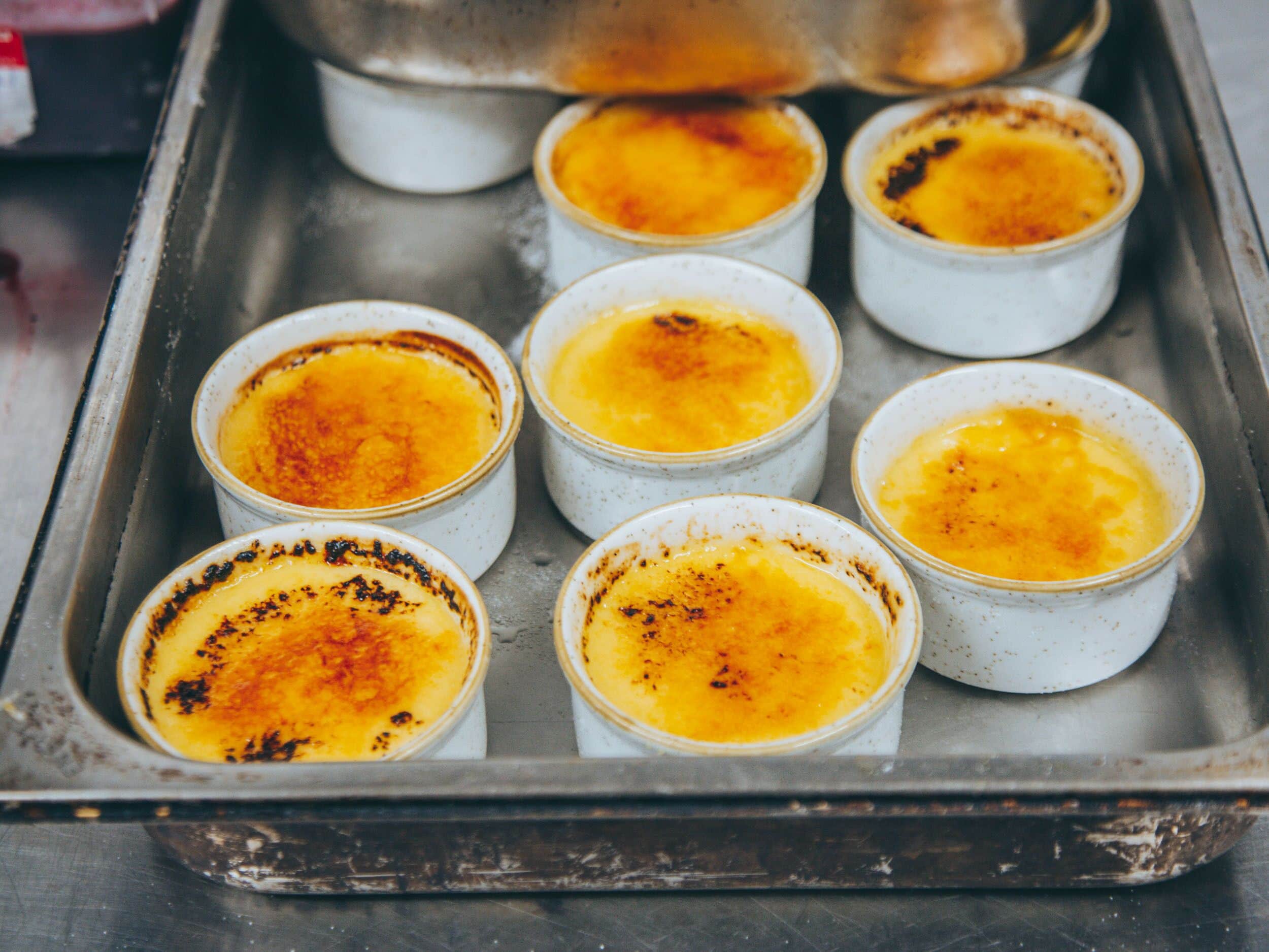 A tray with several ramekins containing crème brûlée.