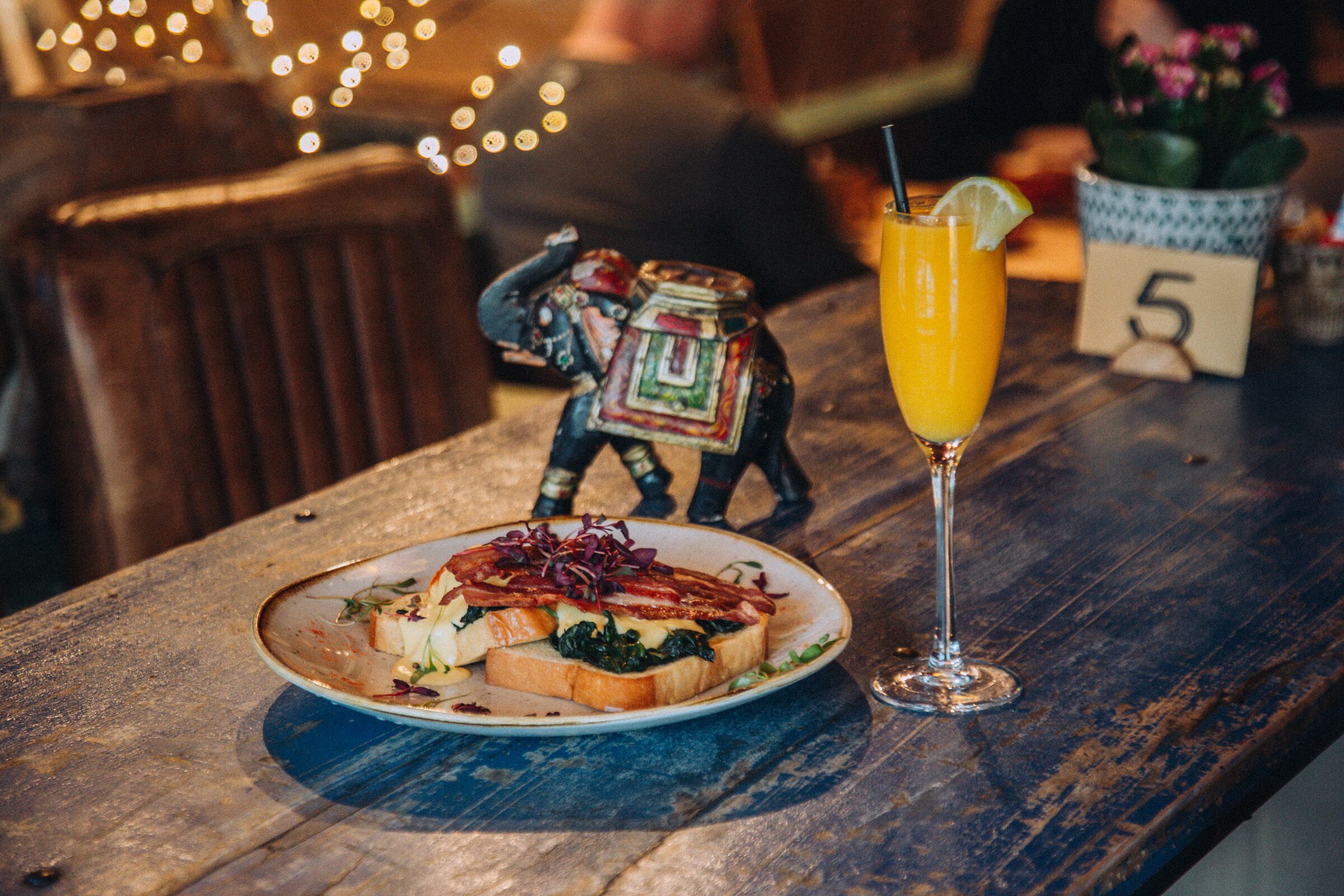 A wooden table with a plate of food and a glass of orange juice.
