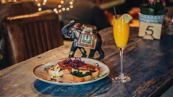 A wooden table with a plate of food and a glass of orange juice.