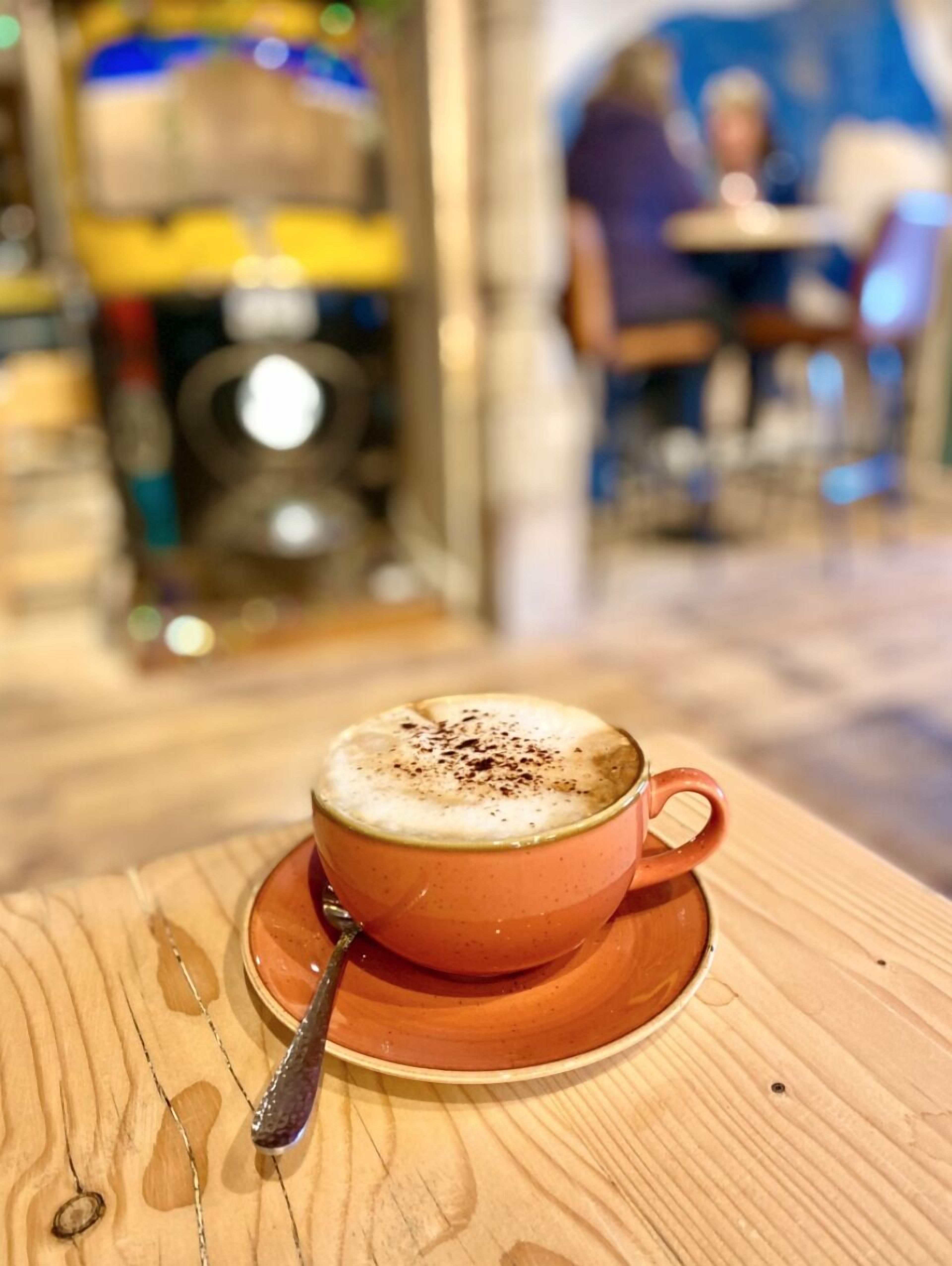En kopp kaffe på ett träbord med en sked.