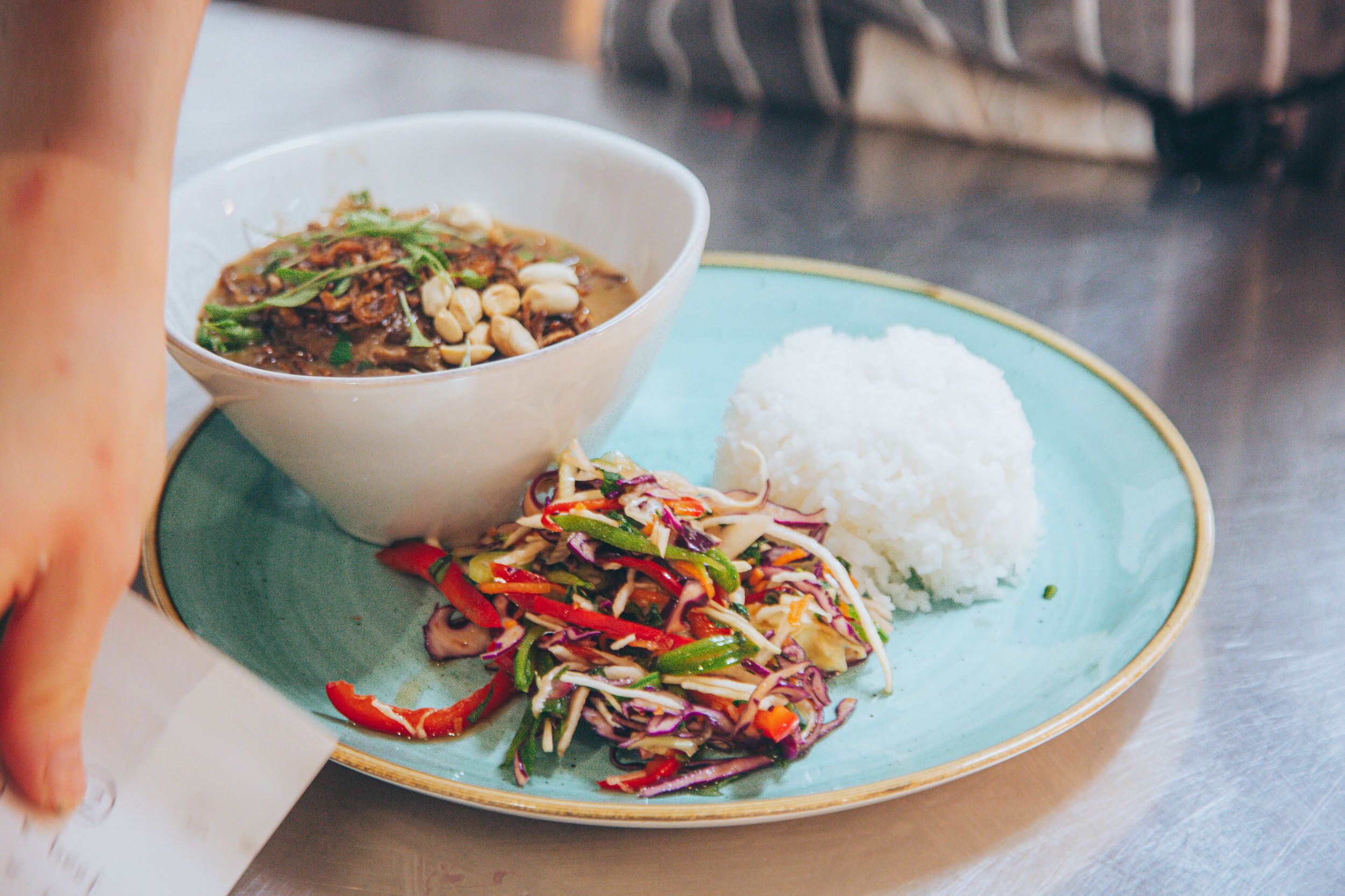 A plate with white rice and a bowl of soup with vegetables.