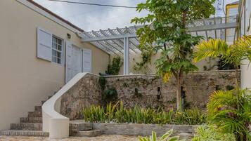 A courtyard with a stone wall, a white staircase, and various plants.