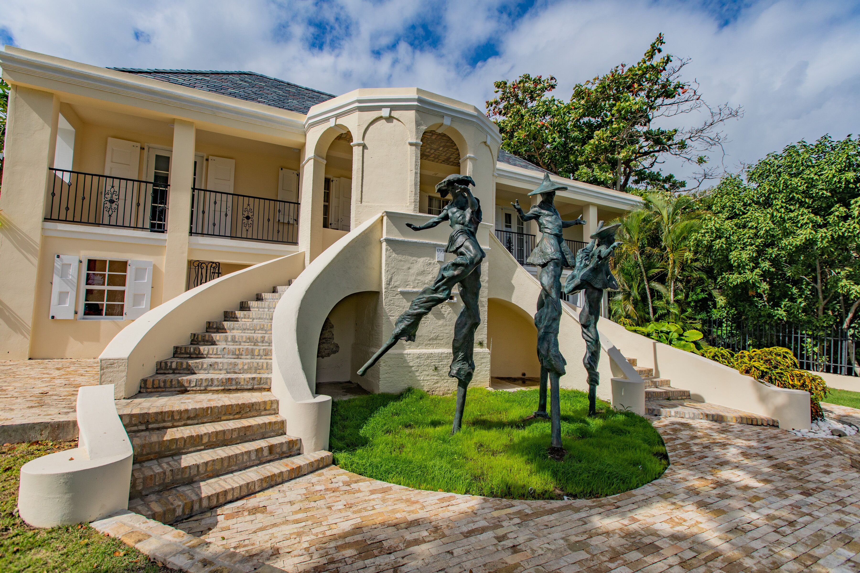 Ein Gebäude mit einer zentralen Treppe, einem Balkon und einer Statue davor.