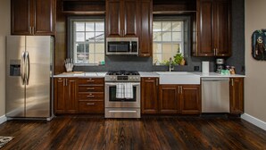 Cozinha moderna com armários de madeira escura, eletrodomésticos de aço inoxidável e uma grande janela que oferece luz natural.