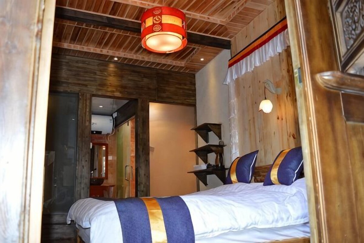 Un dormitorio con cama, techo de madera y lámpara roja.
