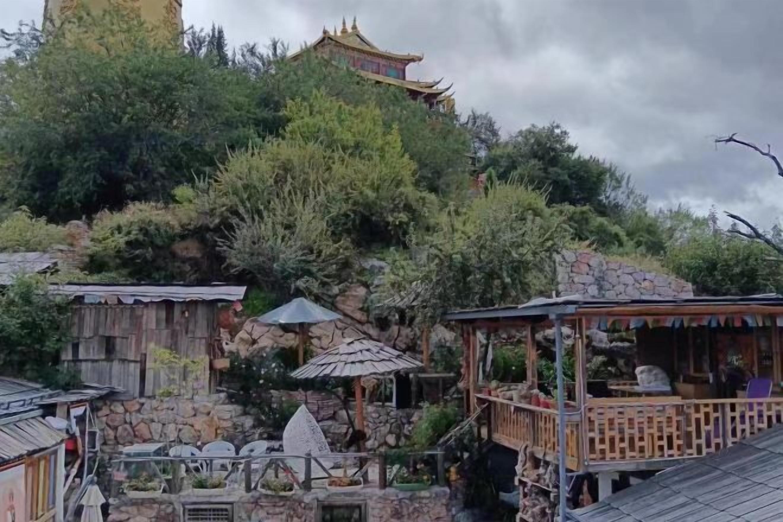 A traditional building with a pagoda-style roof, surrounded by lush greenery and stone structures.