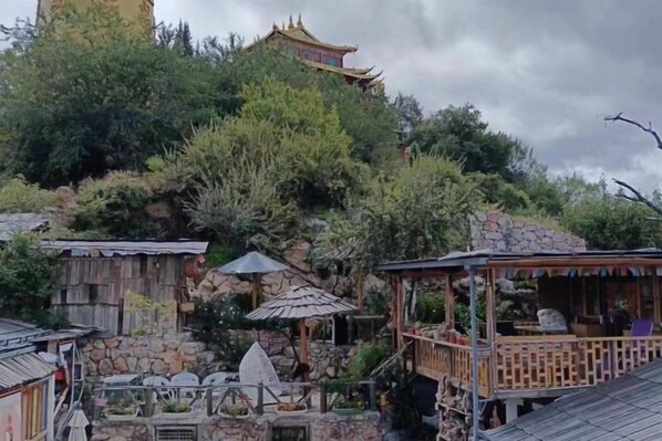 A traditional building with a pagoda-style roof, surrounded by lush greenery and stone structures.