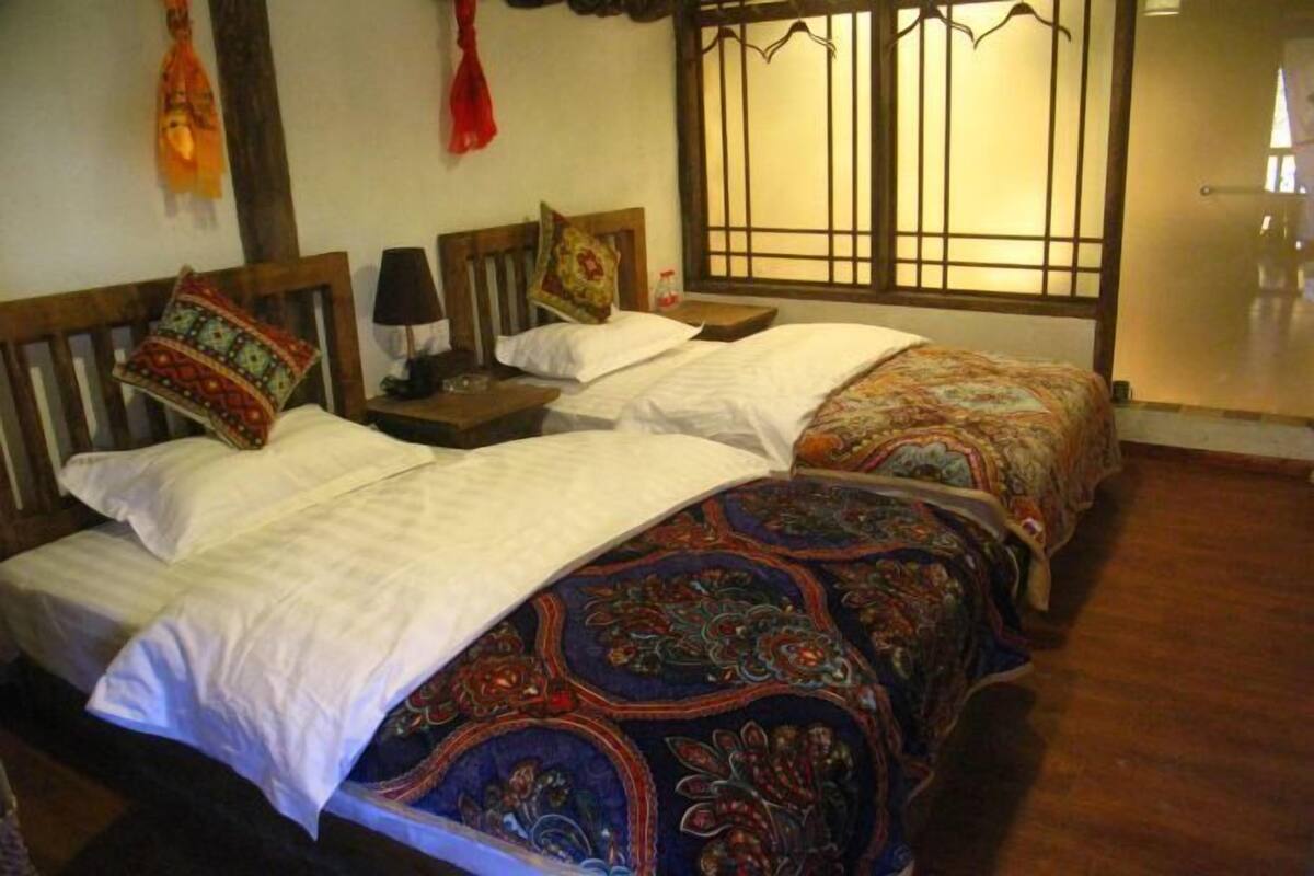 A traditional room with two beds, wooden headboards, and a window with a decorative screen.