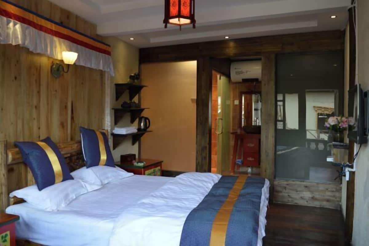 A bedroom with a bed, wooden walls, a shelf with items, and a door leading to another room.