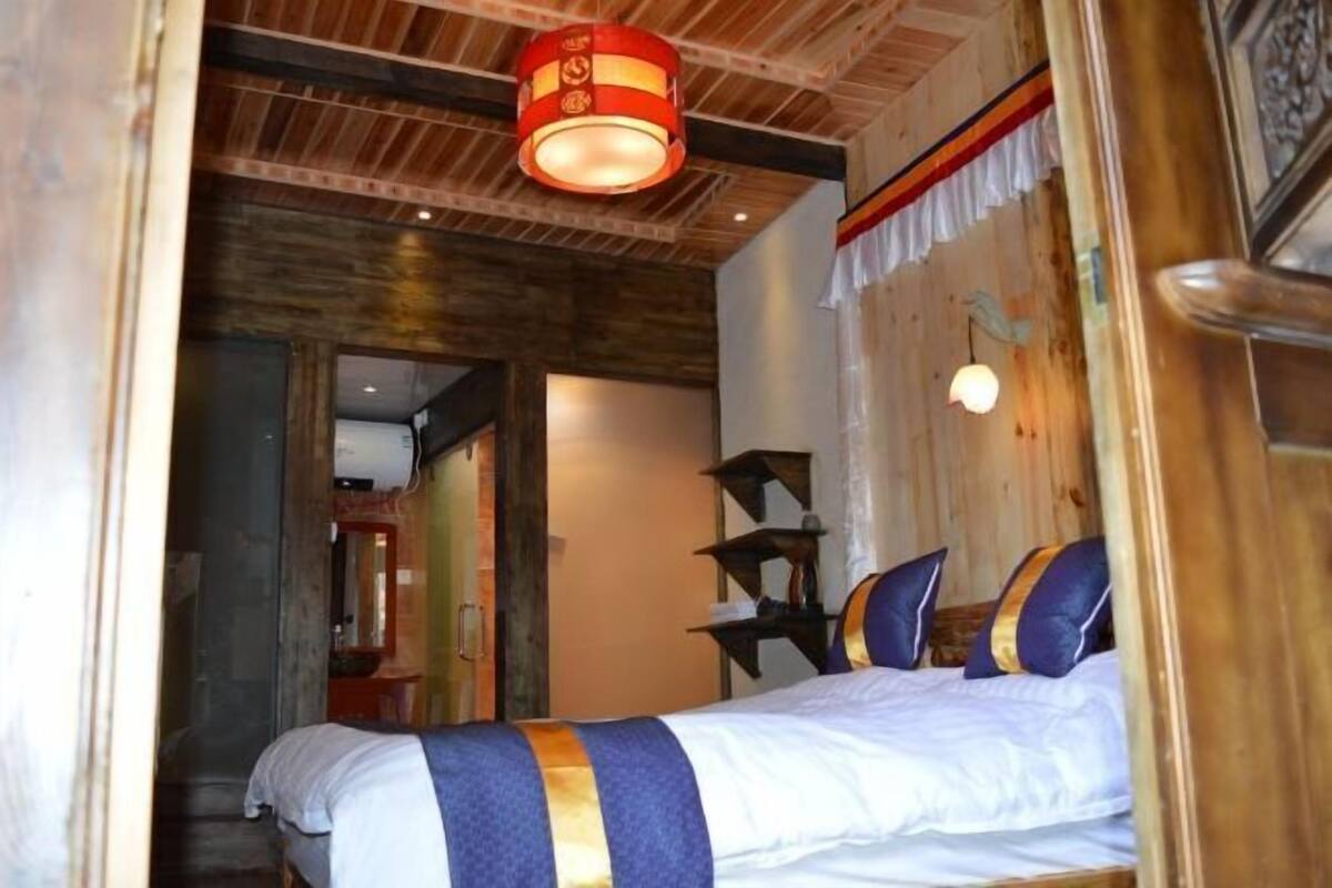 A room with a bed, wooden ceiling, and a red lantern.
