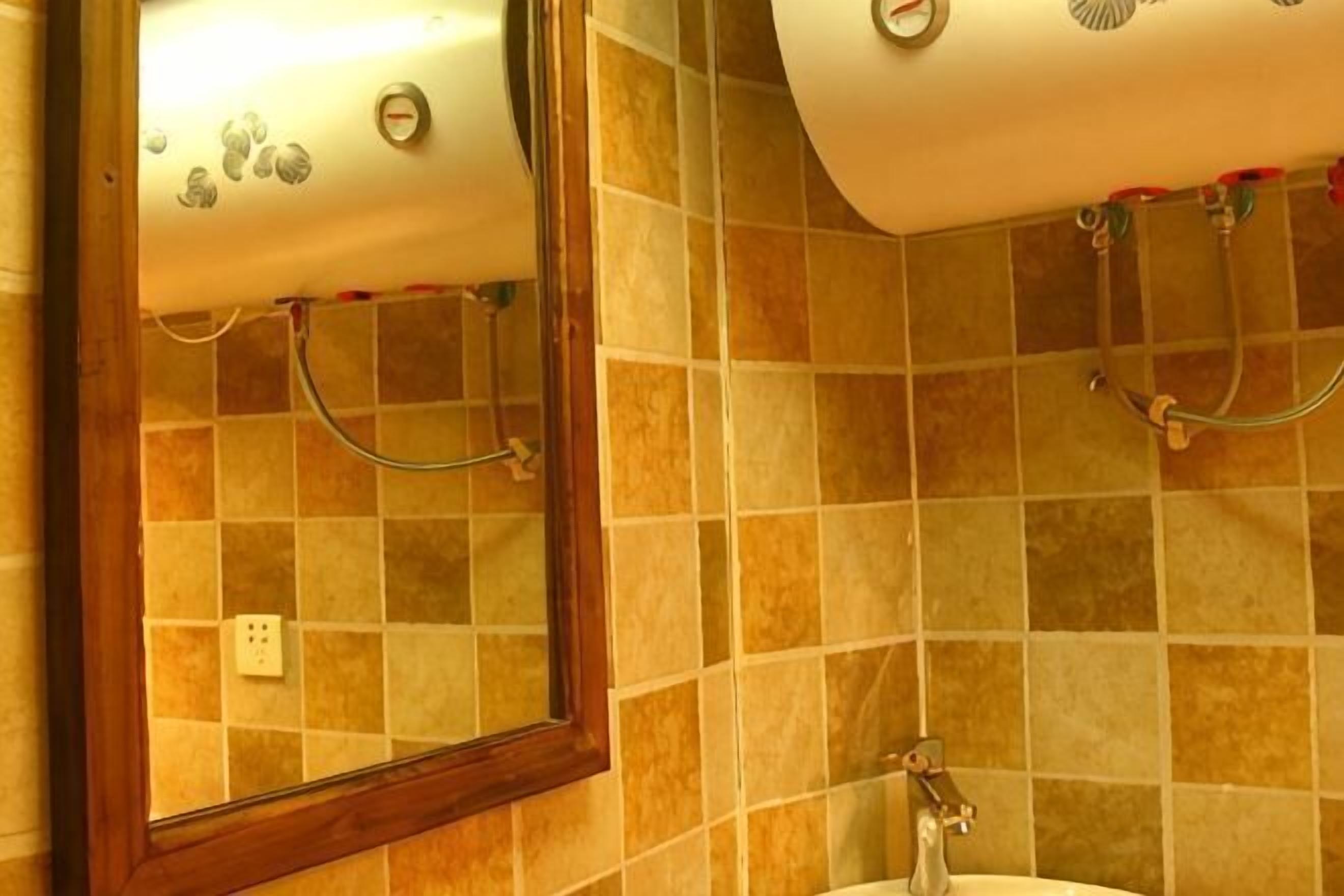 A bathroom with a tiled wall, a sink, and a mirror.