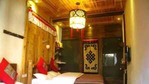 Une pièce avec un plafond en bois, un lit recouvert d’une literie blanche et rouge, une couvre-lit à motifs et un luminaire décoratif suspendu au plafond.