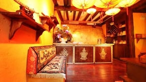 A traditional interior with a wooden bench, a counter with decorative elements, and hanging paper lanterns. - Prayer Wheel Sightseeing Inn (Shangri-La)