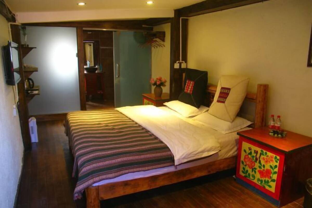 A bedroom with a wooden bed, a nightstand with a floral design, and a mirror above the bed.