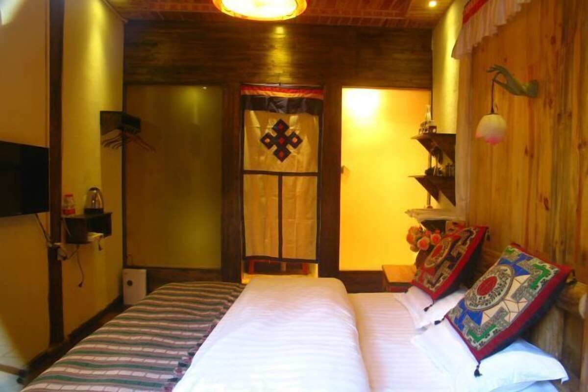 Una habitación con cama, puerta de madera, estante con objetos y lámpara colgante.