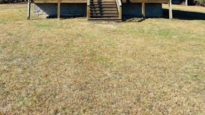 A two-story wooden cabin with a green metal roof, a front porch with steps, and a small circular window. - Cabin with private pond. A peaceful escape (Deer Lodge)