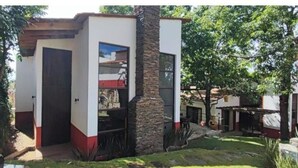 A modern building with a stone pillar, a door, and a small outdoor area with plants. - Mid Town Tapalpa 2 (Tapalpa)