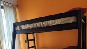A bunk bed with a wooden frame and beige bedding in a room with orange walls and wooden flooring. - Mid Town Tapalpa 2 (Tapalpa)