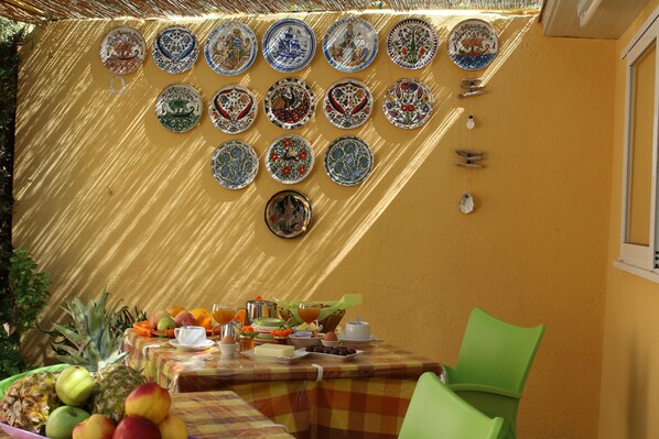 A dining area with a table set for breakfast, featuring fruits, eggs, and a variety of dishes.