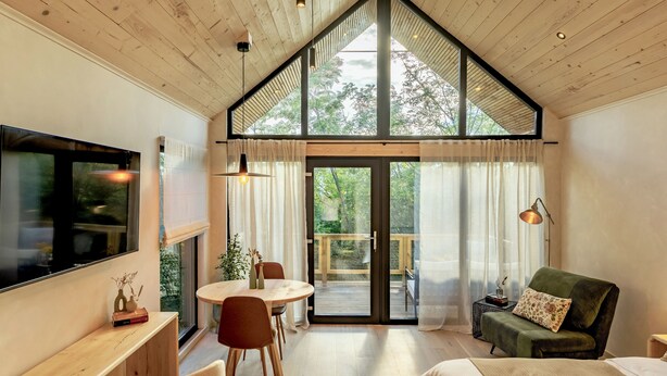 A modern interior with a wooden ceiling, a large TV, a dining area, and a sofa.