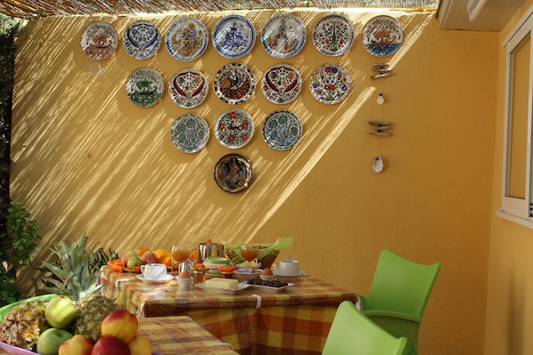 Un comedor con una mesa lista para el desayuno, con frutas, huevos y una variedad de platos.