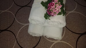 A stack of white towels with a floral arrangement on a patterned carpet. - Georgia Old Town Apartments - Double Room (N.5), Georgia Old Town Apartments Rhodes (Ρόδος,)